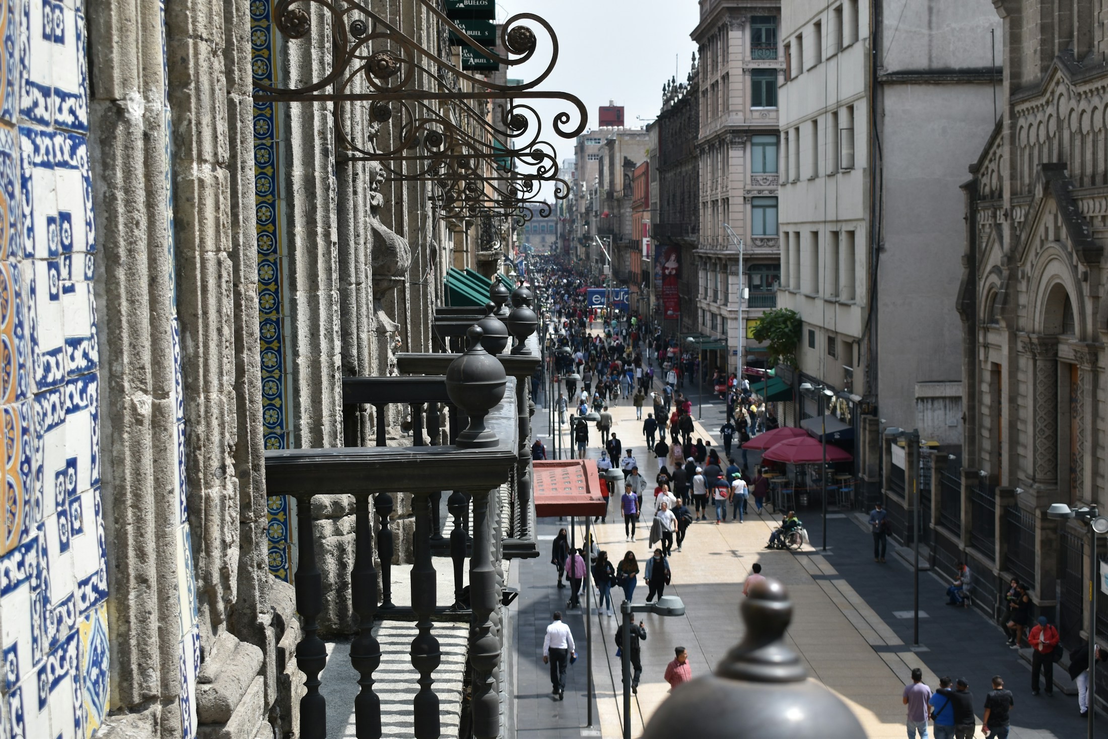 People walking along a street beside historic architecture in Mexico City