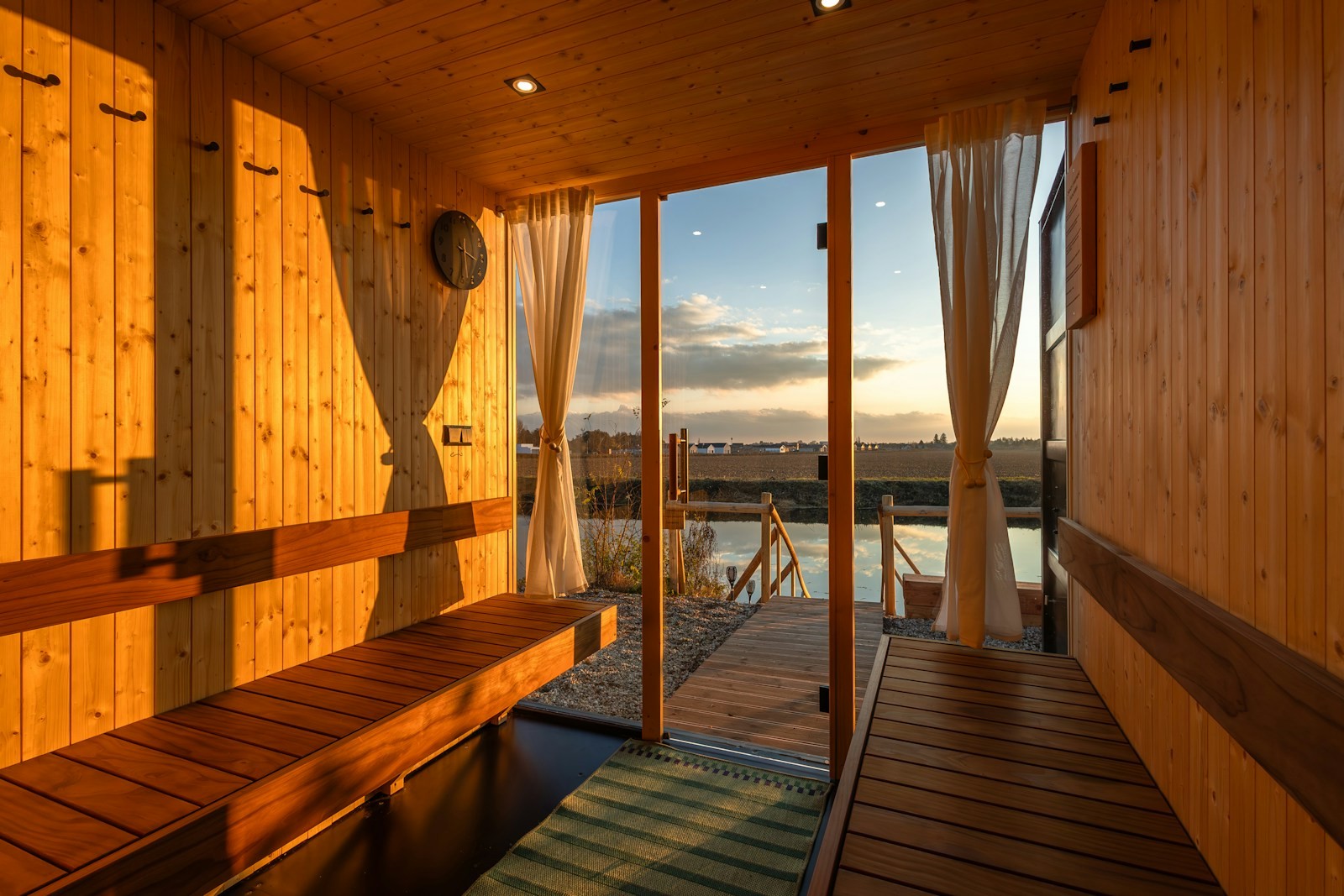 Evening light falling across wooden benches in a sauna overlooking the water